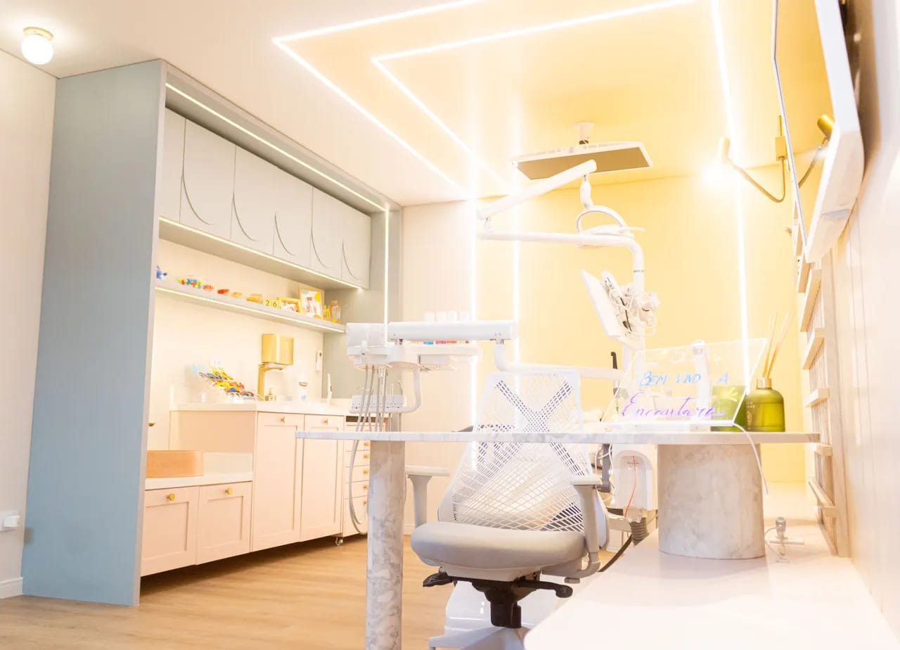 Consultório amarelo e claro da Encantare com cadeira odontológica e bancada