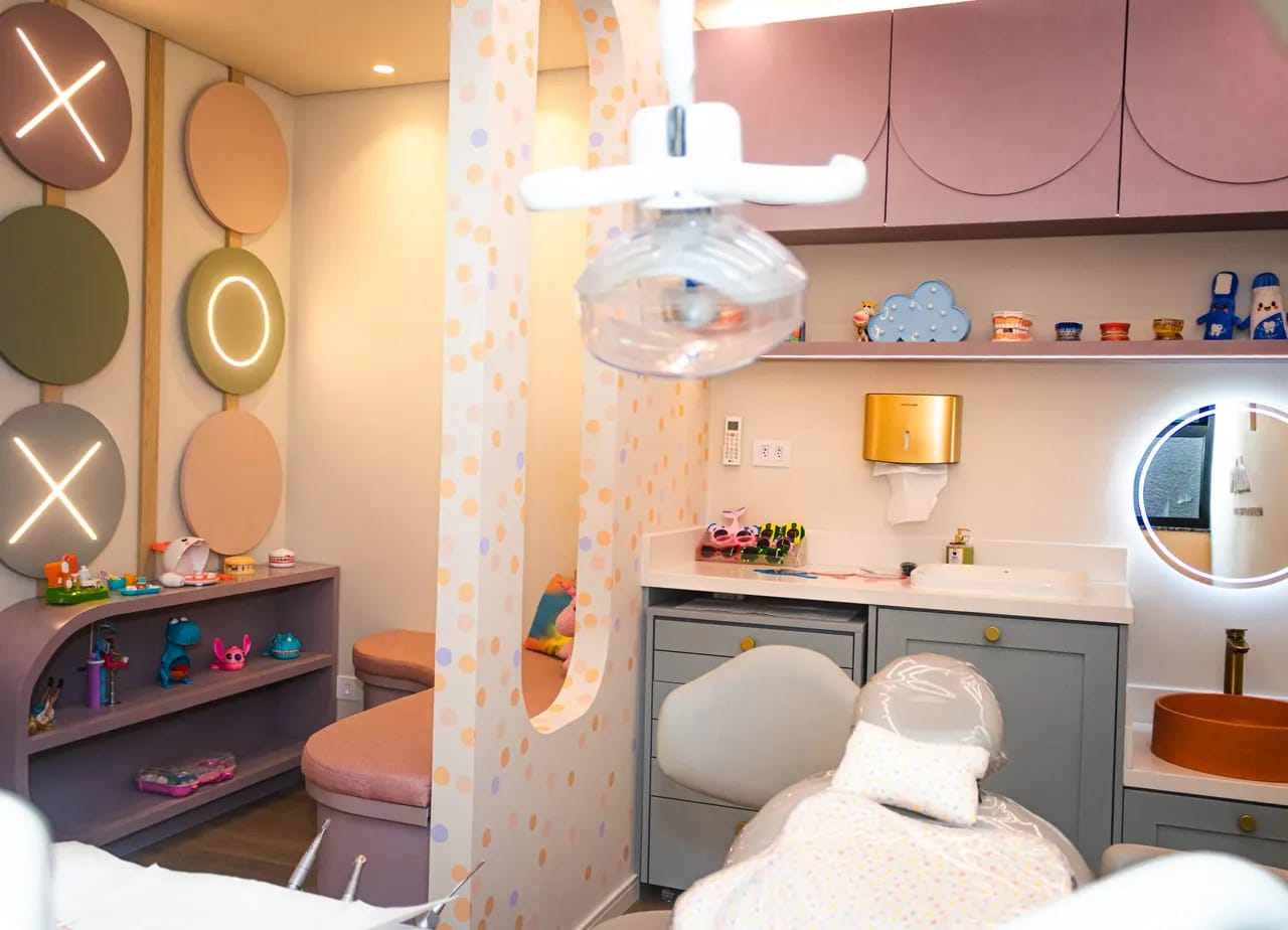 Consultório infantil da Encantare com parede de jogo da velha, prateleira de brinquedos e cadeira odontológica