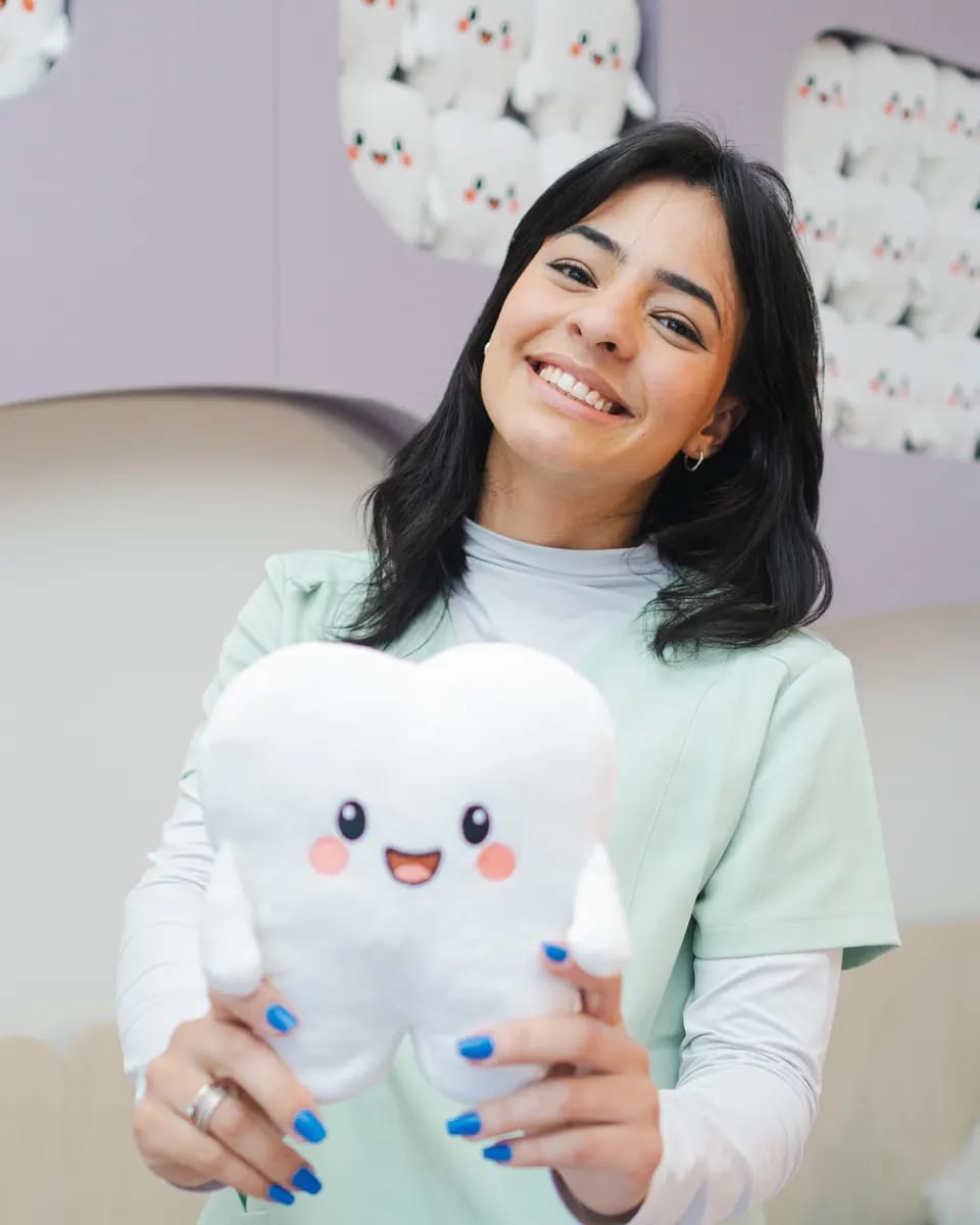 Maria, assistente da Encantare, segurando um dente de pelúcia
